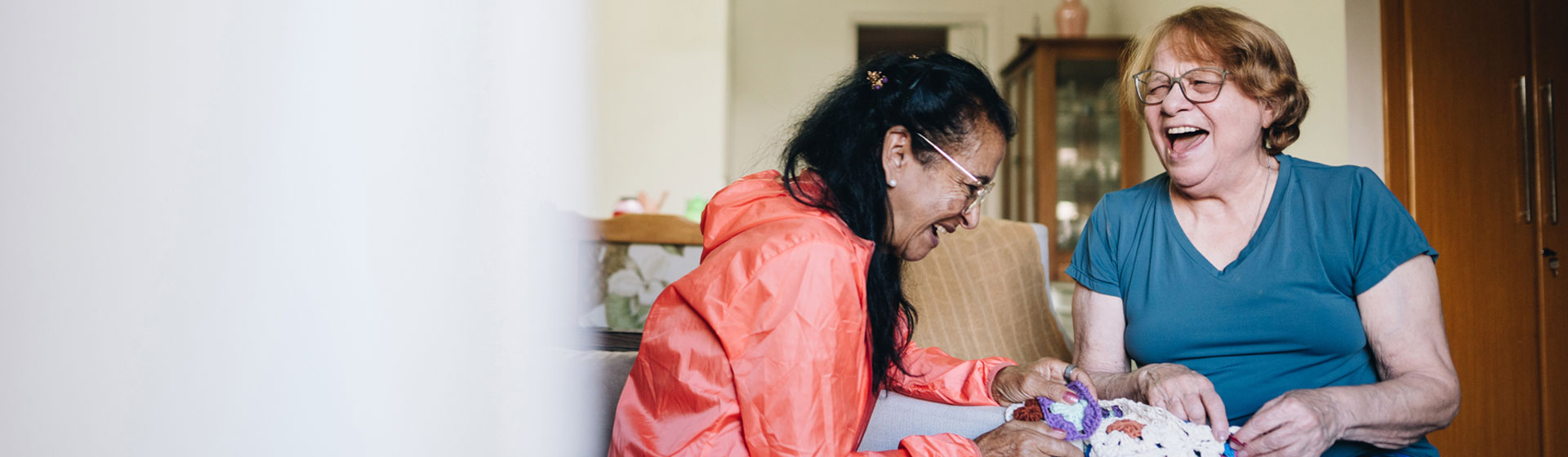 Mother and daughter laughing while crocheting 