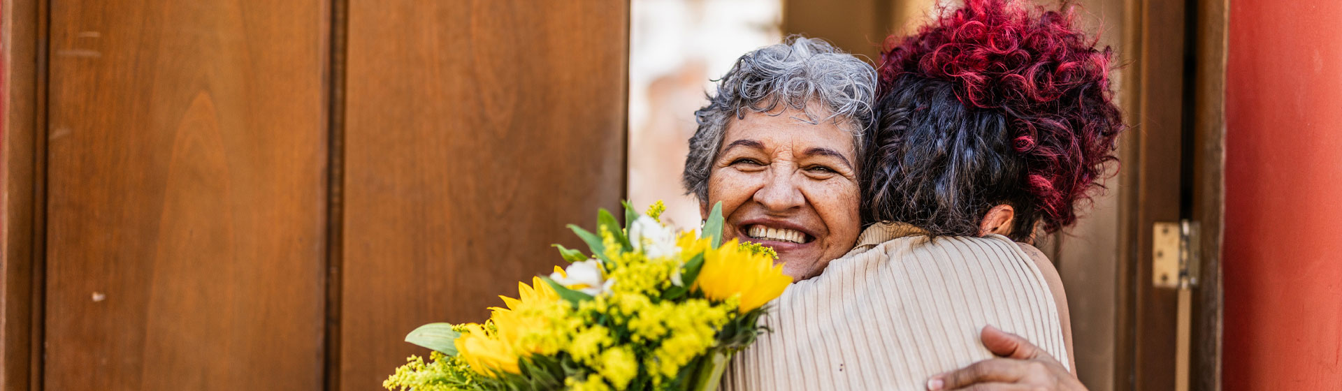 Woman hugging her grandmother with flowers