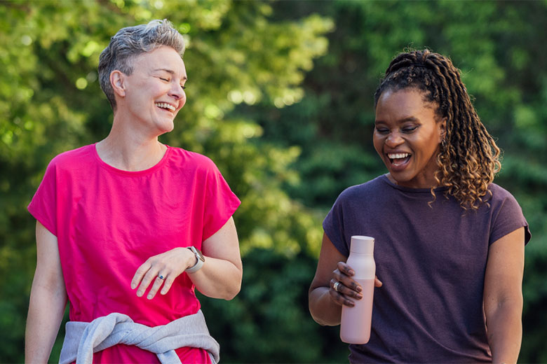 Two woman walk outside and laugh together
