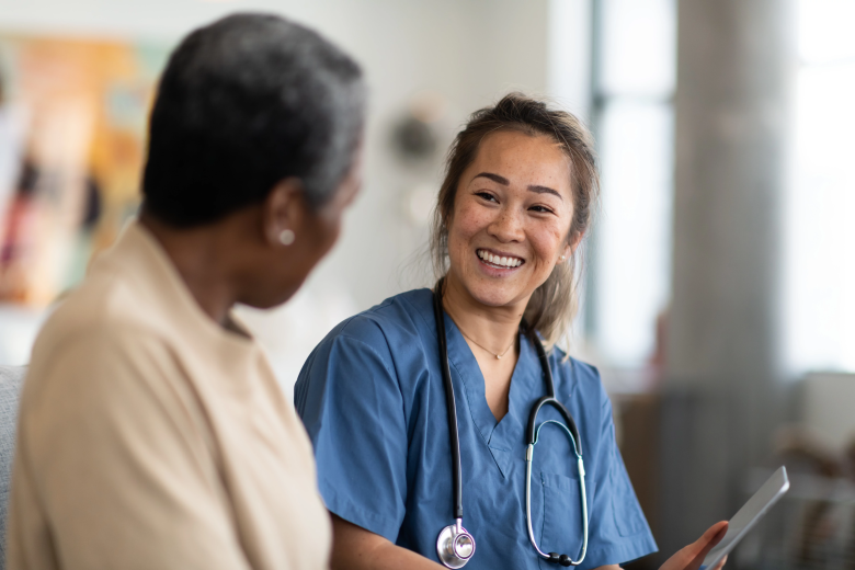 A woman meets with a patient in a health care setting.