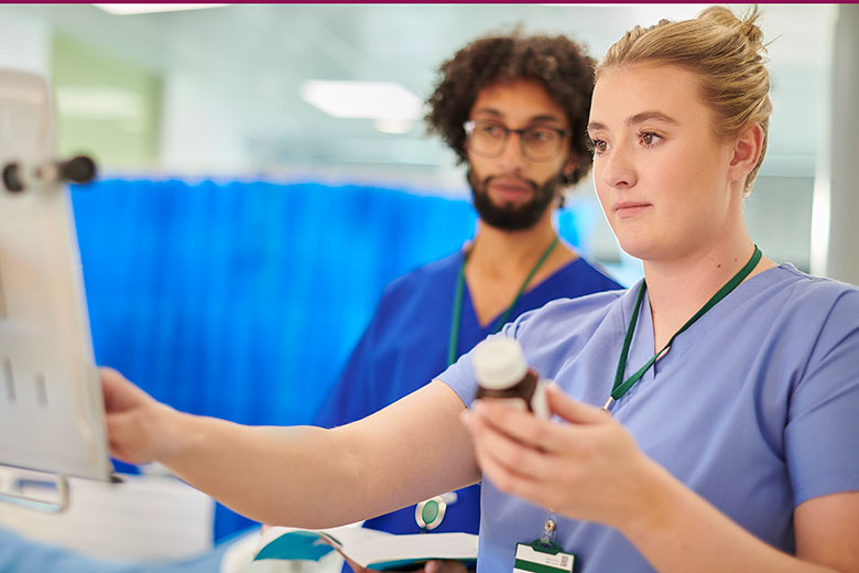 Medical student looks on as clinician enters information into computer