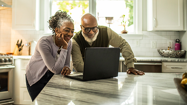 Older couple looks at laptop in their kitchen